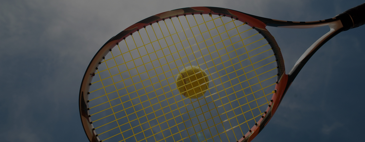 Tennis racket and ball against a dramatic court backdrop