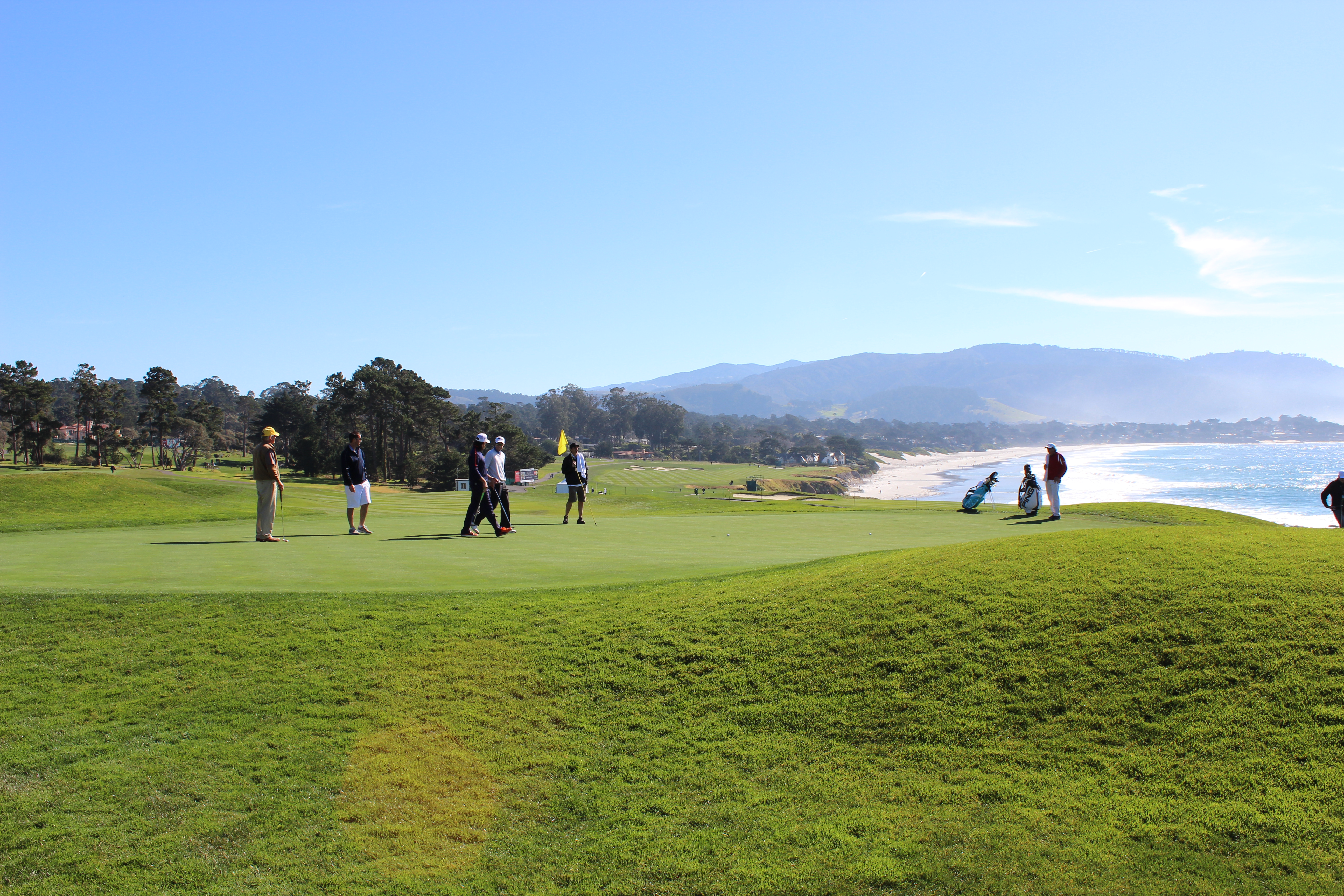 Players on a green at Pebble Beach overlooking the coast; the 2027 Invitational venue is to be confirmed