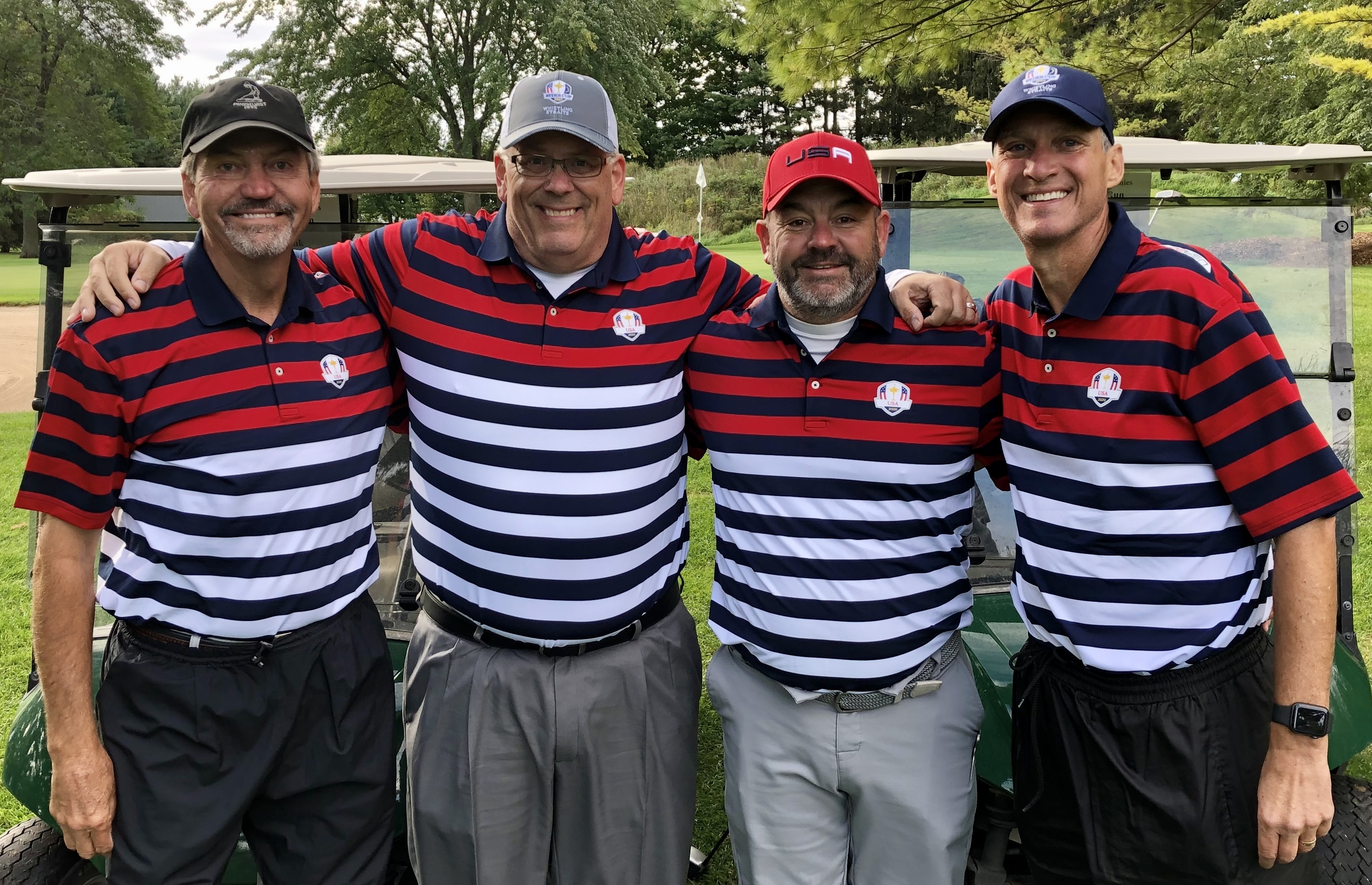 Four golfers wearing matching red, white and navy shirts at a previous ISM Ryder Cup outing