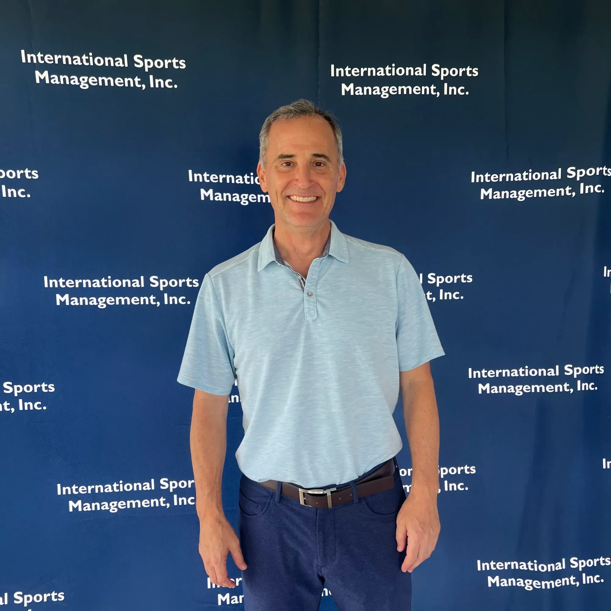 Steve Sands of NBC Sports and Golf Channel standing in front of a blue International Sports Management step-and-repeat banner.