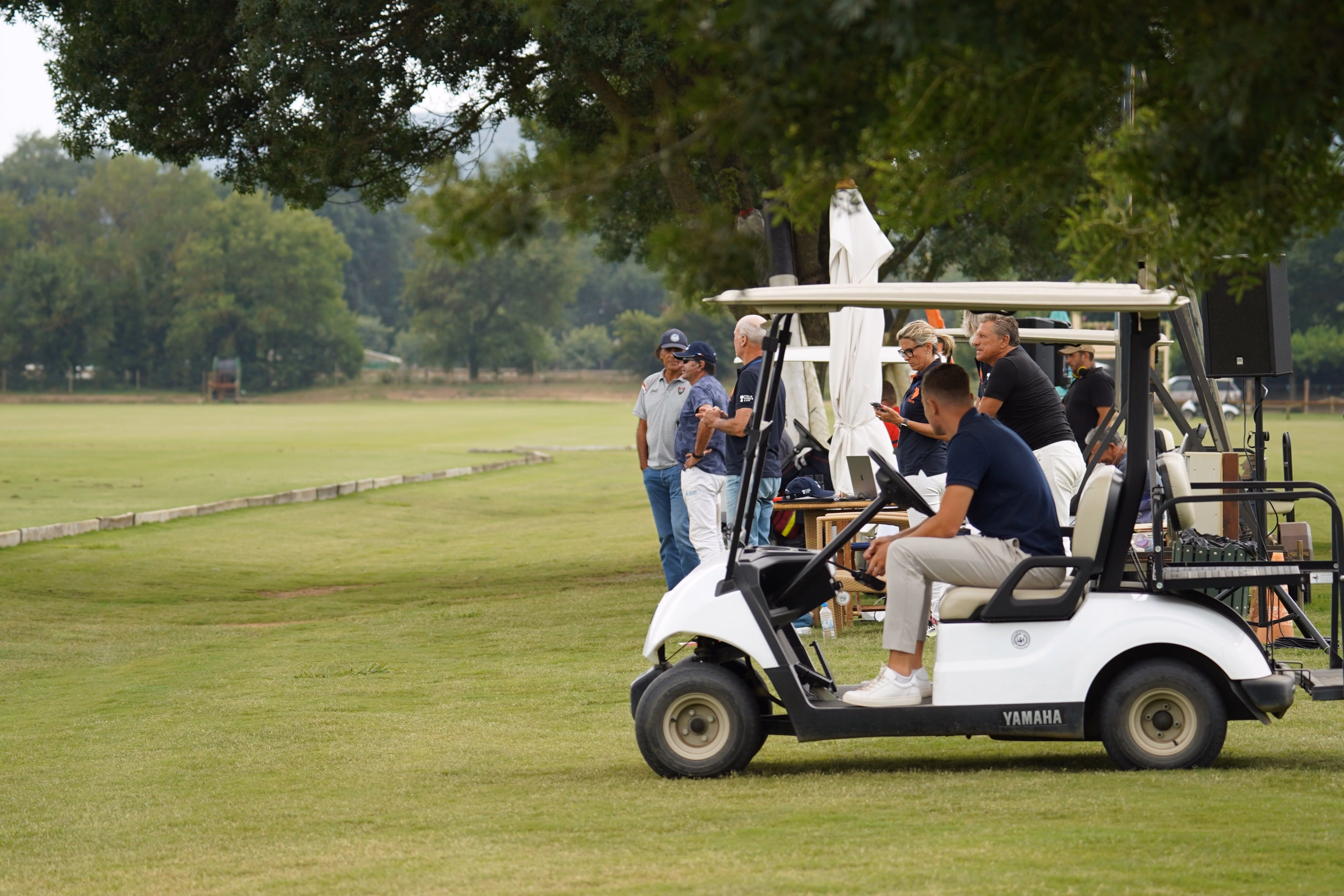 A group of golfers gathering beside their carts on a golf course